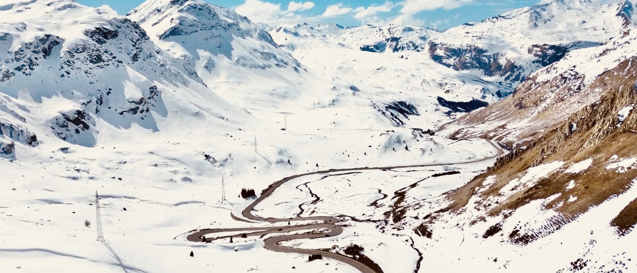 Valle nevado de los Alpes suizos con la carretera de puerto serpenteando